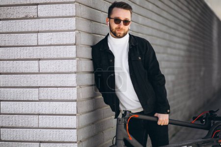 Téléchargez les photos : Bel homme équitation en ville sur scooter - en image libre de droit