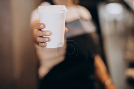 Photo for Female barista holding cardboard coffee cup - Royalty Free Image