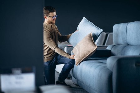 Photo for Young man buying pillows and sofa in furniture store - Royalty Free Image