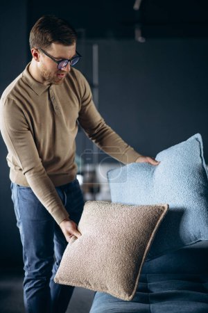 Photo for Young man buying pillows and sofa in furniture store - Royalty Free Image