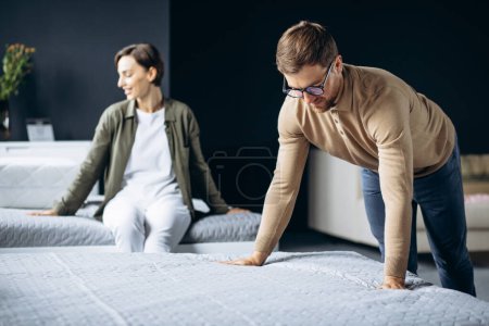 Photo for Couple buying new bed with orthipedic mattress in furniture store - Royalty Free Image