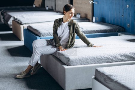 Téléchargez les photos : Femme couchée sur le lit avec oreiller orthopédique dans un magasin de meubles - en image libre de droit