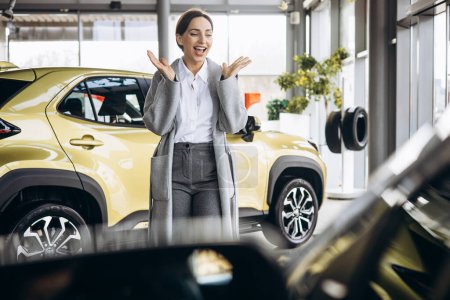 Téléchargez les photos : Femme d'affaires choisissant une voiture dans une salle d'exposition de voiture - en image libre de droit