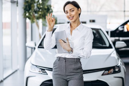 Photo for Young saleswoman with tablet in a car showroom - Royalty Free Image