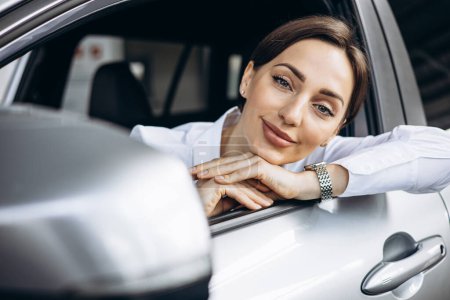 Téléchargez les photos : Femme souriante et assise dans une voiture - en image libre de droit