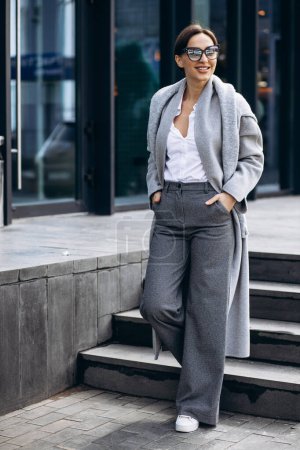 Foto de Hermosa mujer de negocios en abrigo gris fuera del edificio de oficinas - Imagen libre de derechos