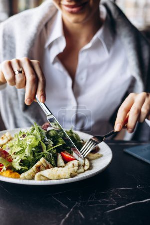 Téléchargez les photos : Femme buvant du coctail et mangeant de la salade dans un café - en image libre de droit