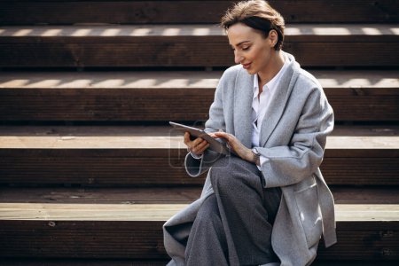 Foto de Mujer de negocios sentado en las escaleras y trabajando en la tableta - Imagen libre de derechos