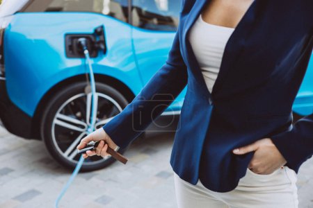 Photo for Woman closing her electric car charging - Royalty Free Image