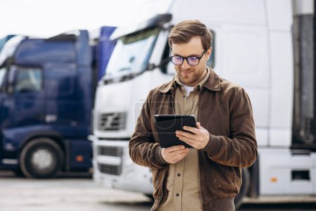 Téléchargez les photos : Chauffeur de camion debout près de son camion et en utilisant une tablette - en image libre de droit