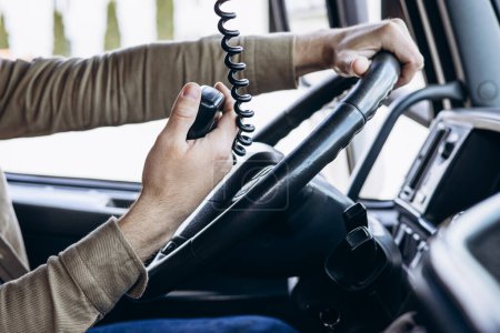 Téléchargez les photos : Chauffeur de camion assis dans la cabine de son camion et utilisant un émetteur radio - en image libre de droit