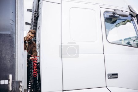 Photo for Truck driver stopped on the road reparing his lorry - Royalty Free Image