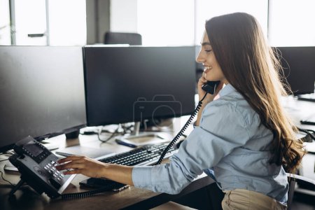 Photo for Young woman secretary talking on the phone at the office - Royalty Free Image