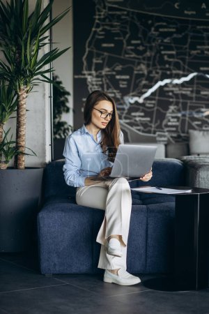 Téléchargez les photos : Jeune femme d'affaires travaillant sur ordinateur portable dans la zone de bureau de refroidissement - en image libre de droit
