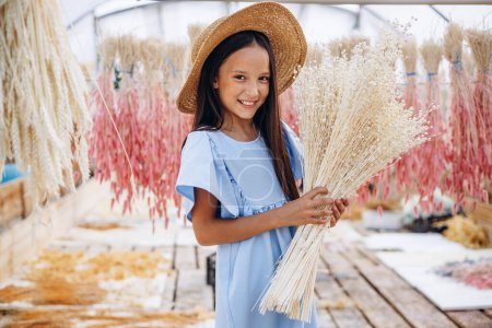 Foto de Linda niña con orejas secas decorativas de maíz - Imagen libre de derechos