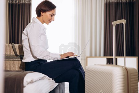 Photo for Business woman working on laptop from a hotel room - Royalty Free Image
