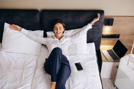 Téléchargez les photos : Femme d'affaires couchée sur un lit dans une chambre d'hôtel - en image libre de droit