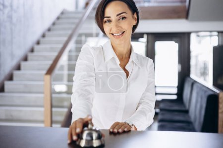 Téléchargez les photos : Femme d'affaires au lobby de l'hôtel sonne la cloche du comptoir - en image libre de droit