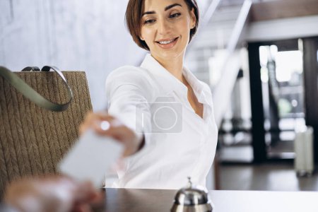 Téléchargez les photos : Femme prenant la clé de la chambre à la réception de l'hôtel - en image libre de droit