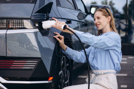 Téléchargez les photos : Femme d'affaires charge sa voiture électrique - en image libre de droit