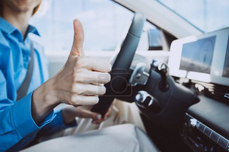 Photo for Woman sitting in electric car and showing thumbs up sign - Royalty Free Image
