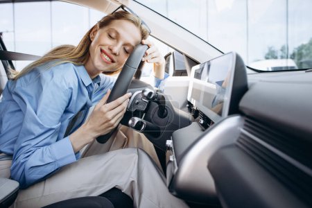 Téléchargez les photos : Femme souriant et tenant volant dans sa voiture électrique - en image libre de droit