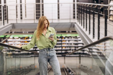 Téléchargez les photos : Femme sur l'escalator parlant sur son téléphone au magasin de matériaux d'intimidation - en image libre de droit