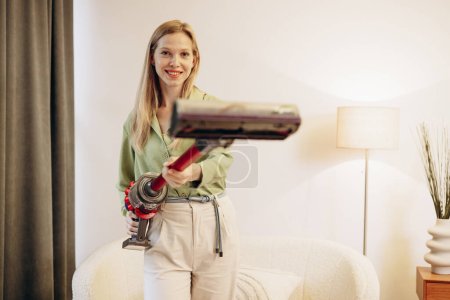 Téléchargez les photos : Femme faisant du travail à la maison et utilisant un aspirateur sans fil - en image libre de droit