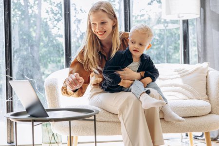 Téléchargez les photos : Mère avec son fils utilisant un ordinateur portable ensemble à la maison - en image libre de droit