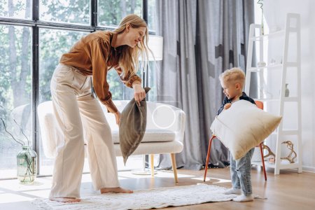 Photo for Mother with her little son playing with pillows at home - Royalty Free Image