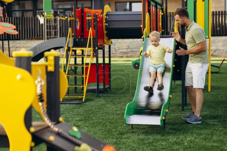 Photo for Father with son going down the slide on the playground - Royalty Free Image