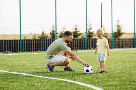 Foto de Padre con hijo jugando fútbol en el campo de fútbol - Imagen libre de derechos