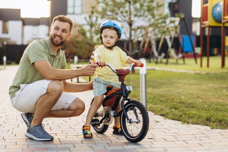 Photo for Father teaching his little son to ride a bicycle - Royalty Free Image