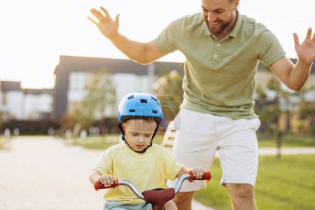 Téléchargez les photos : Père apprenant à son petit fils à faire du vélo - en image libre de droit