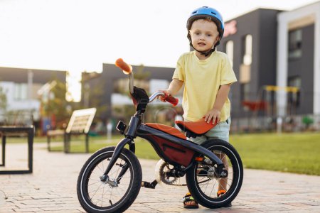 Téléchargez les photos : Petit garçon mignon apprenant à faire du vélo - en image libre de droit