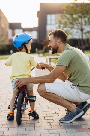 Foto de Padre enseñando a su pequeño hijo a andar en bicicleta - Imagen libre de derechos