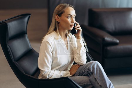 Photo for Business woman sitting in the office chair and talking on the phone - Royalty Free Image