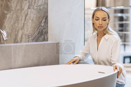 Téléchargez les photos : Femme choisissant bain dans salle de bain shwroom, matériaux de construction - en image libre de droit