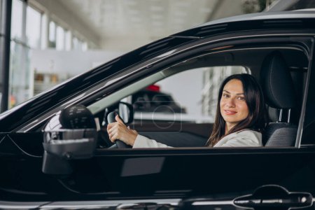 Photo for Woman sitting in her new car in a car showroom - Royalty Free Image