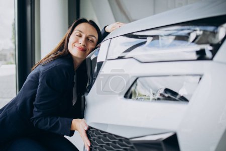 Foto de Mujer abrazando un coche nuevo en una sala de exposición de coches - Imagen libre de derechos