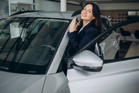Foto de Mujer de ventas en la sala de exposición del coche con las llaves del coche y de pie junto al coche - Imagen libre de derechos