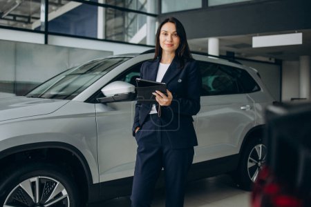 Photo for Woman using tablet and choosing a car in car showroom - Royalty Free Image