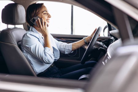 Photo for Business woman sitting in car and talking on the phone - Royalty Free Image