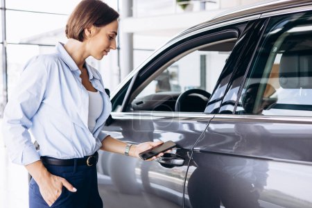 Téléchargez les photos : Femme debout près de sa nouvelle voiture et tenant les clés de la voiture - en image libre de droit
