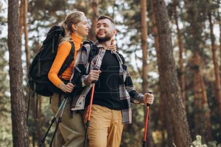 Téléchargez les photos : Couple randonnée avec sacs et bâtons de marche en forêt - en image libre de droit