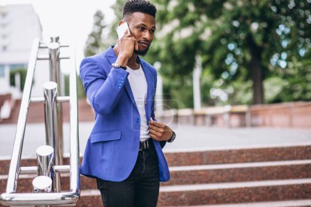 Téléchargez les photos : Africain américain en veste bleue en utilisant le téléphone - en image libre de droit