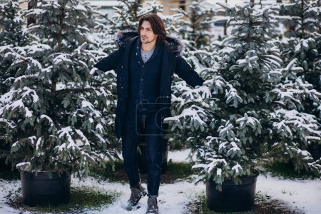 Foto de Hombre guapo eligiendo un árbol de navidad - Imagen libre de derechos