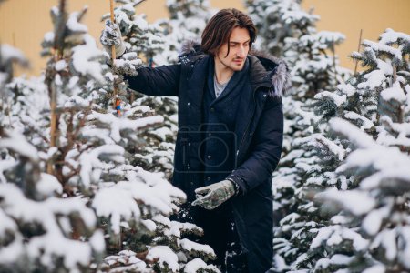 Foto de Hombre guapo eligiendo un árbol de navidad - Imagen libre de derechos