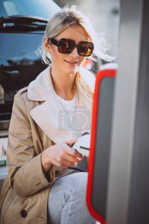 Téléchargez les photos : Femme charge electro voiture à la station-service électrique - en image libre de droit