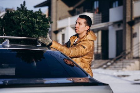 Foto de Hombre entregando el árbol de Navidad en la parte superior del coche - Imagen libre de derechos